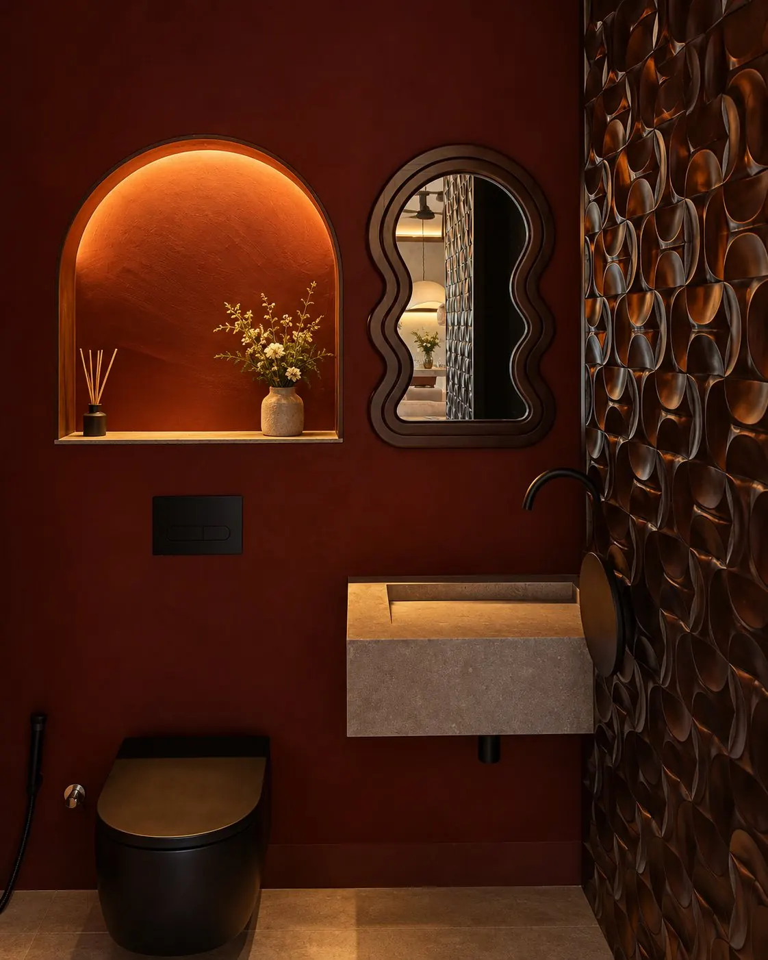 Powder room in deep red plaster with a lit arched niche, a wavy walnut mirror, a stone basin and a wall of bronze relief tiles