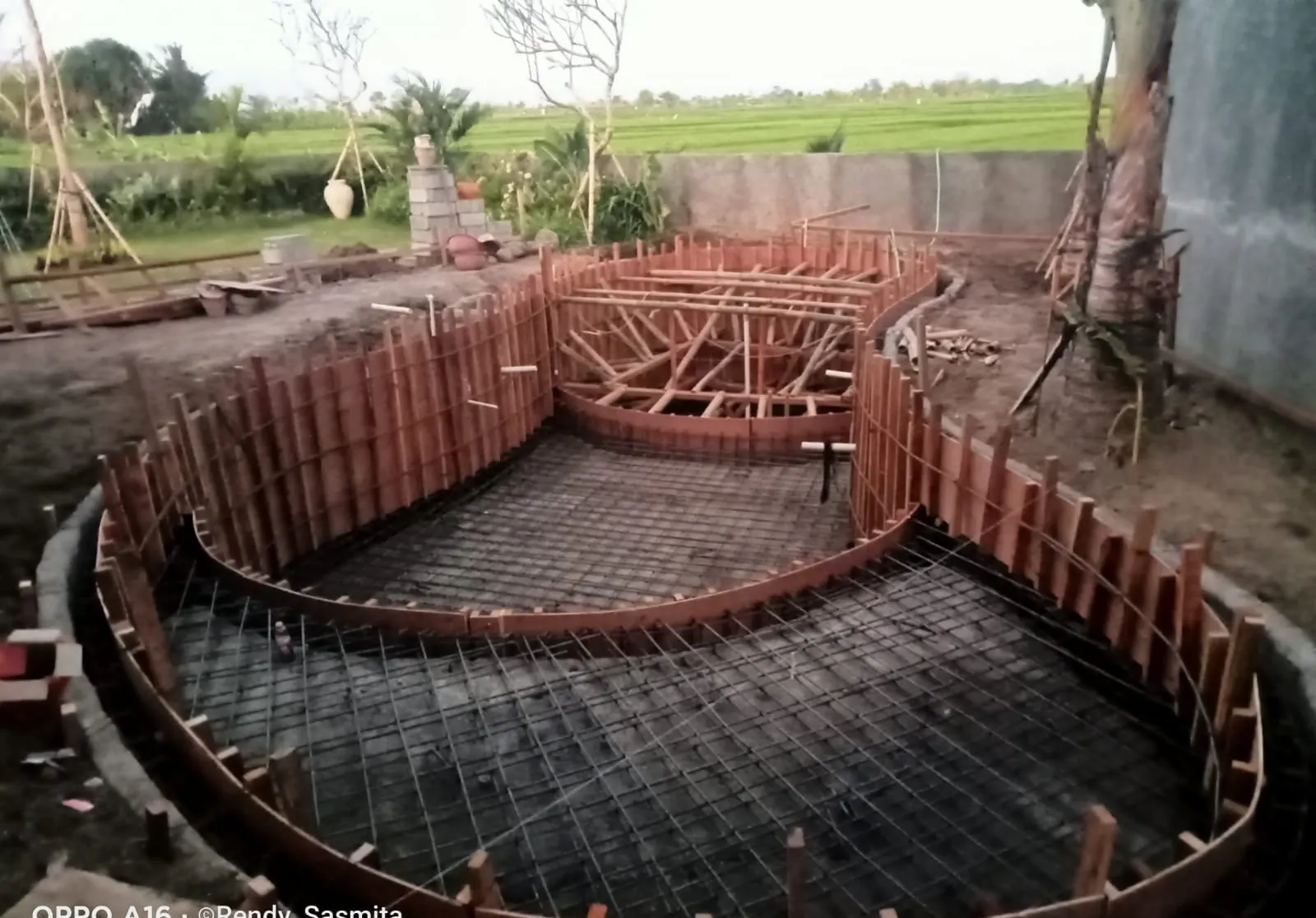Pool with reinforcement mesh and timber formwork, ready for the concrete pour, rice fields behind
