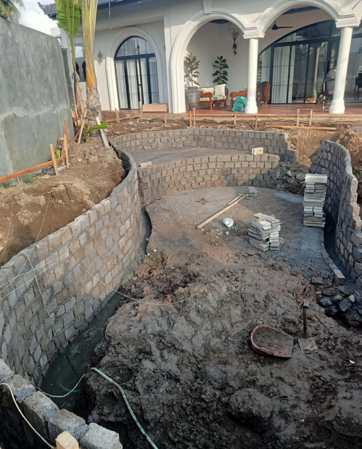 Block walls of the pool with the white arched house behind