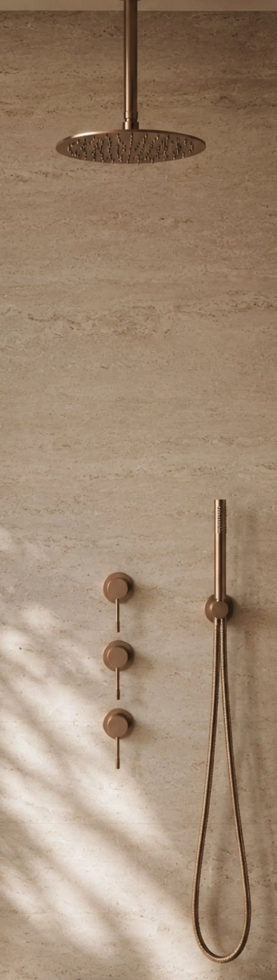 Rose gold ceiling rain shower, three-valve mixer and hand shower on a travertine wall